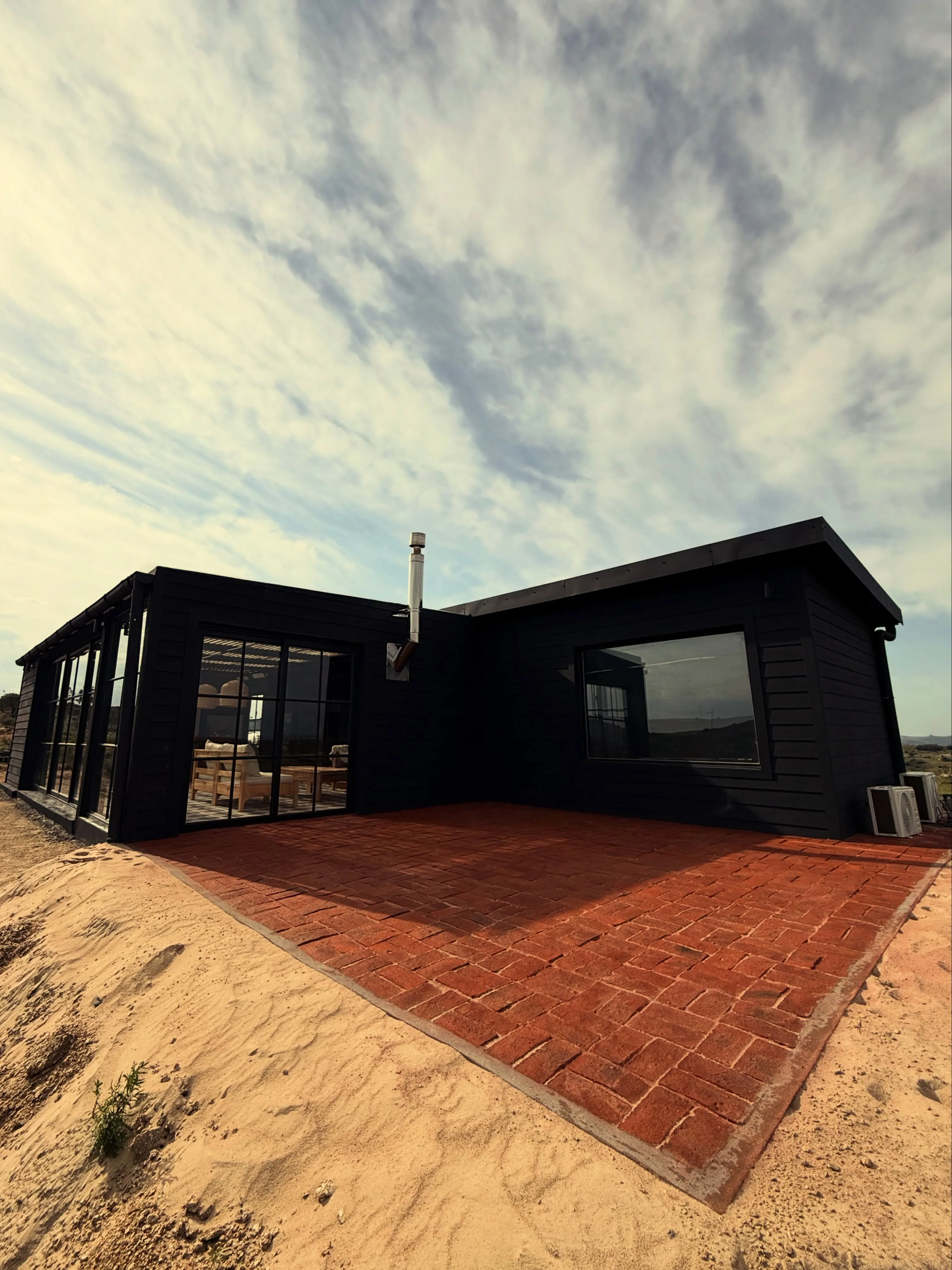 Vivienda de diseño contemporáneo construida por Unión Constructora, revestida en madera negra sobre médanos